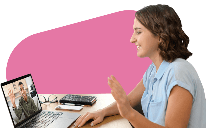 A smiling woman waves to a man on a video call on her laptop