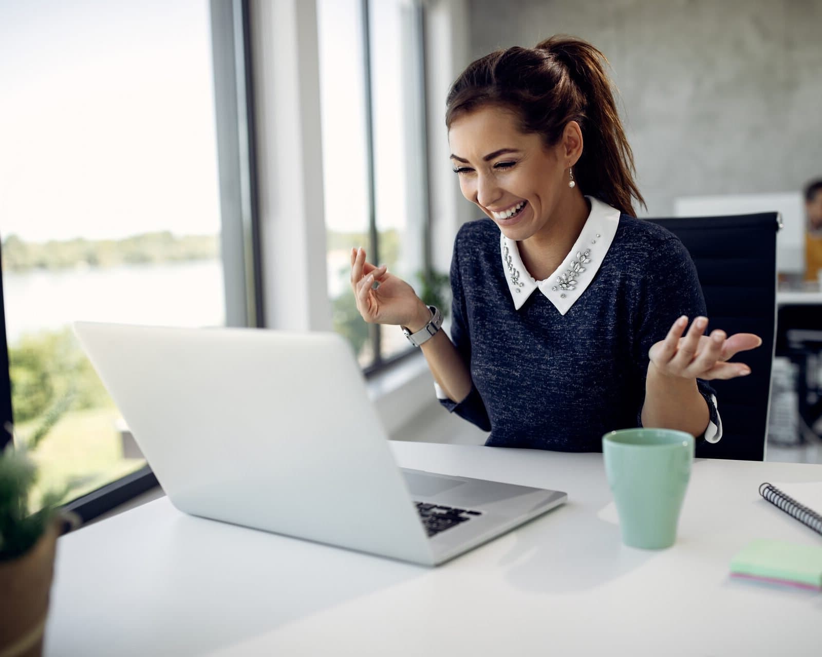 A woman at her laptop talks through a conversation, smiling