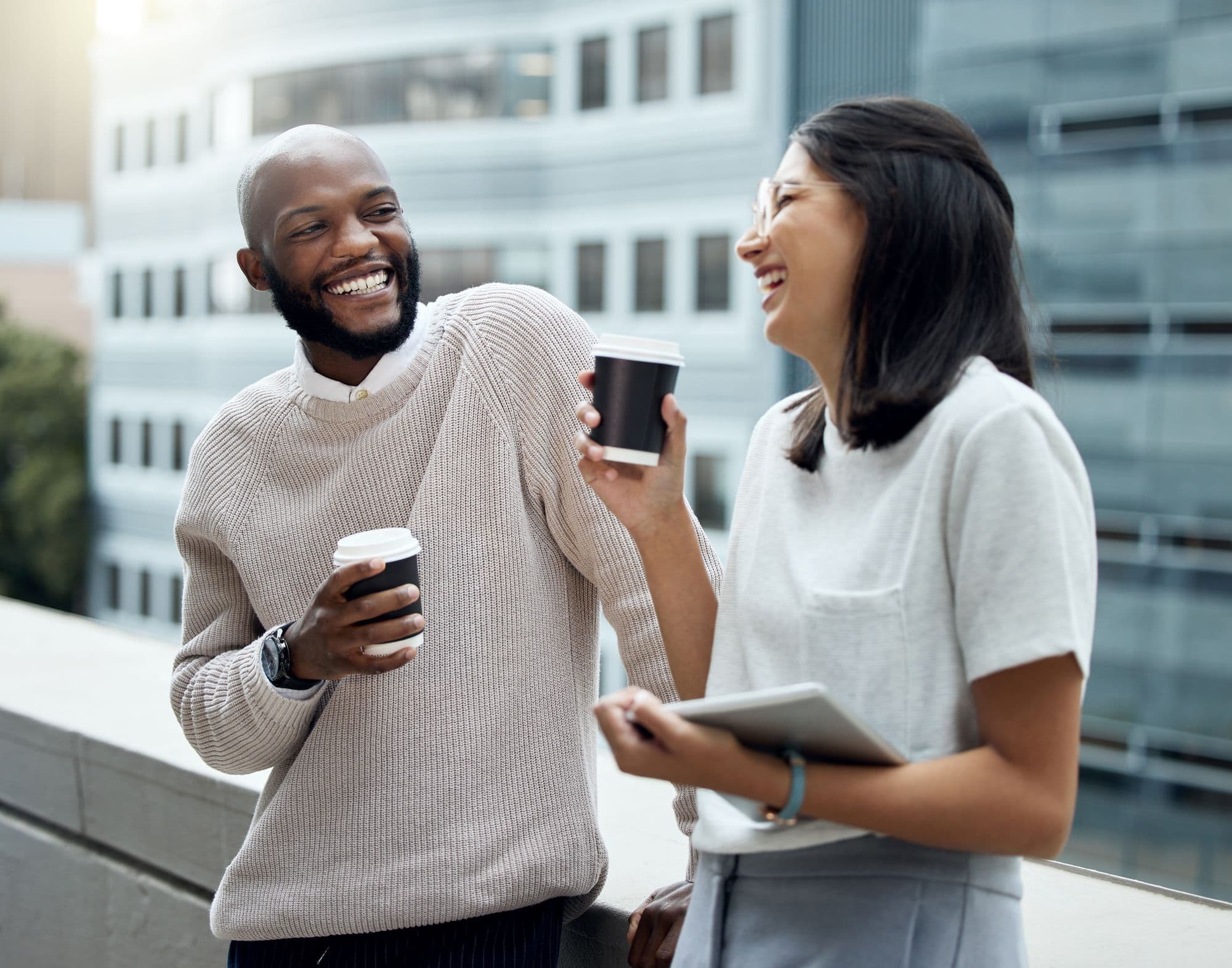 Two colleagues laugh together over coffee