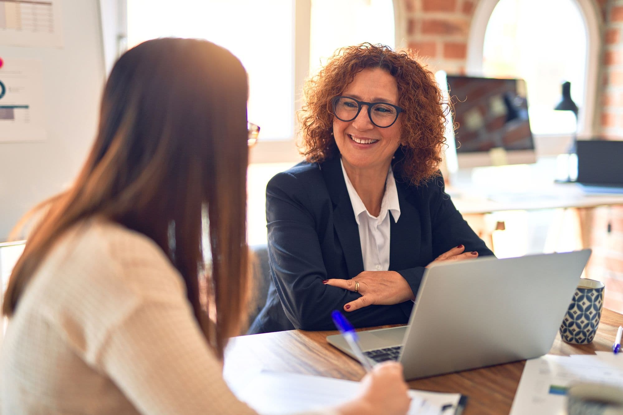 An experienced leader talks with a younger colleague across a desk