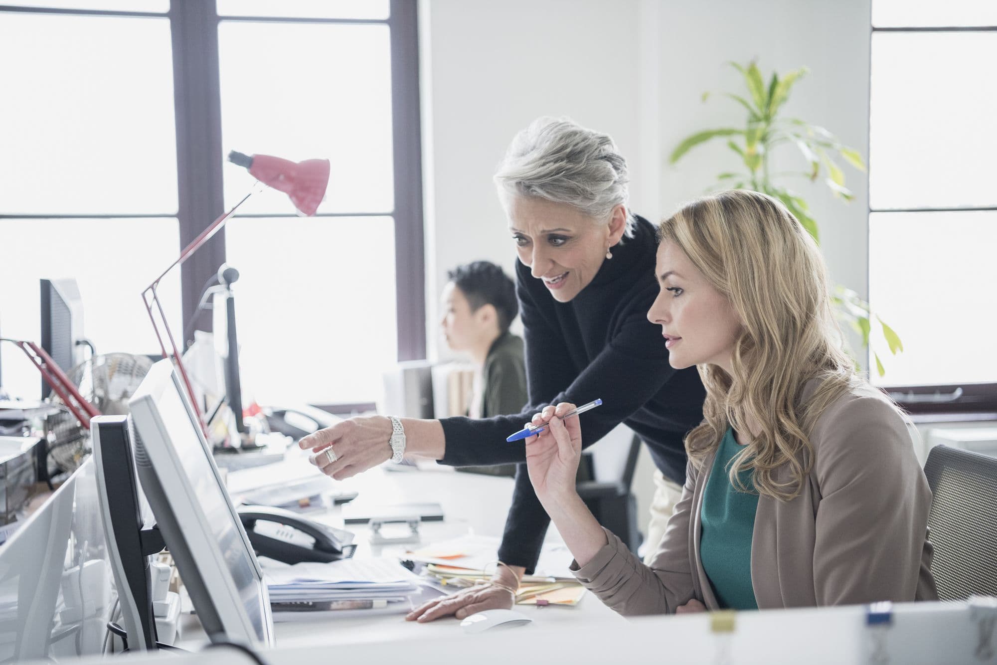 Two women at a computer, one guiding the other