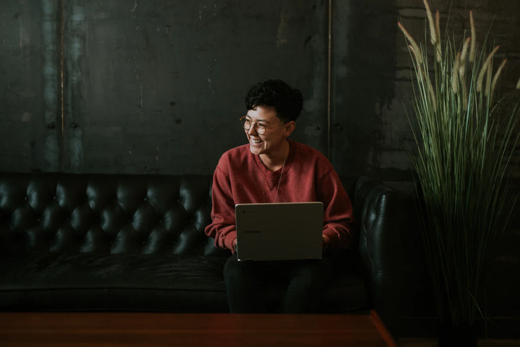 Woman smiling while using a laptop computer researching coaching vs mentoring 