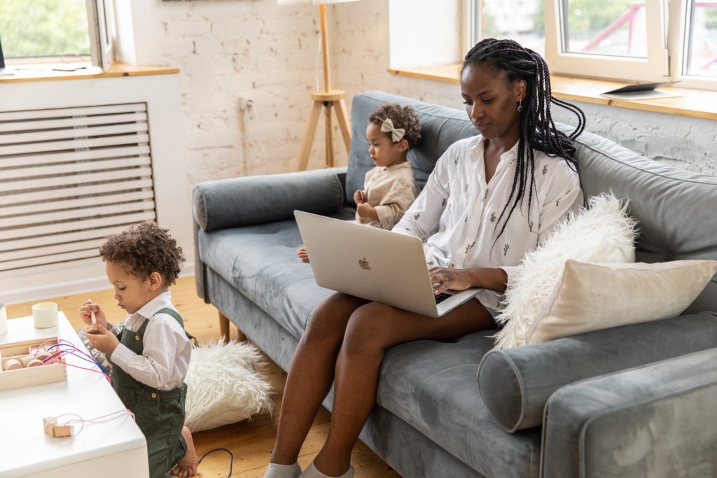 women working remotely in her living while kids play on couch