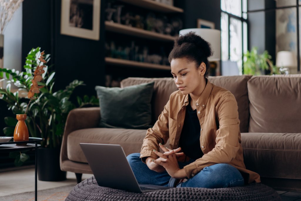 workplace trend: belonging in the workplace, black woman works on her laptop from home, unsure look on her face