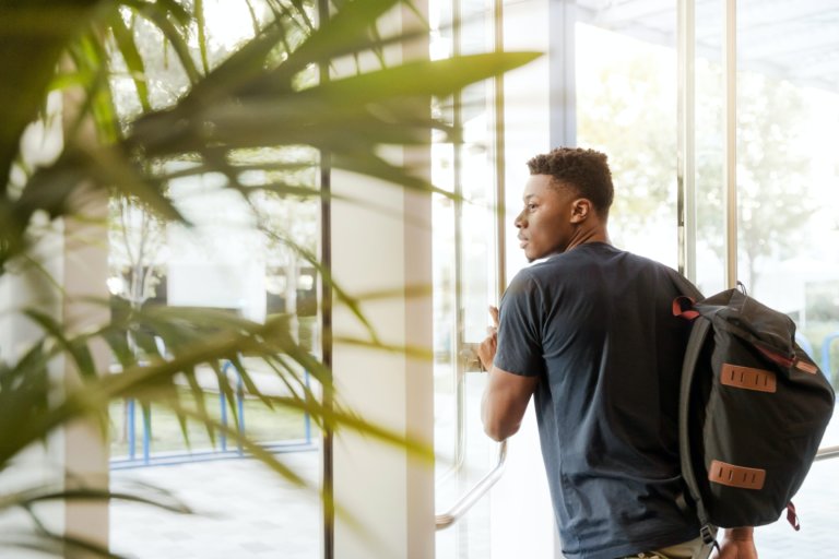black male student with backpack leaving building