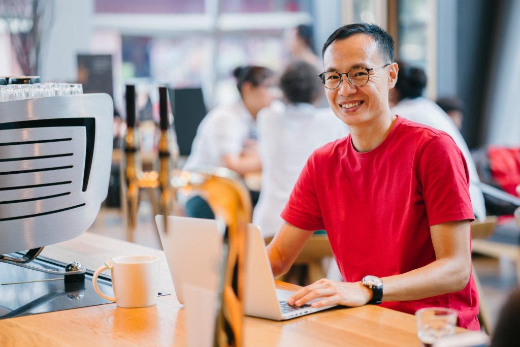 Asian male employee working on laptop in office