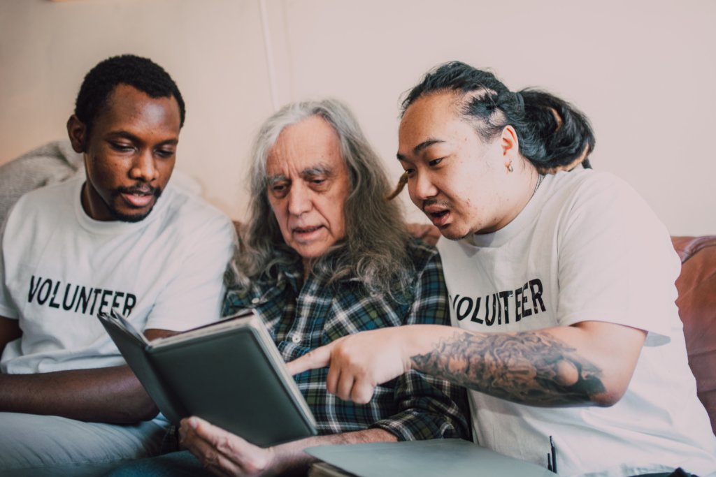 two volunteers help older man read
