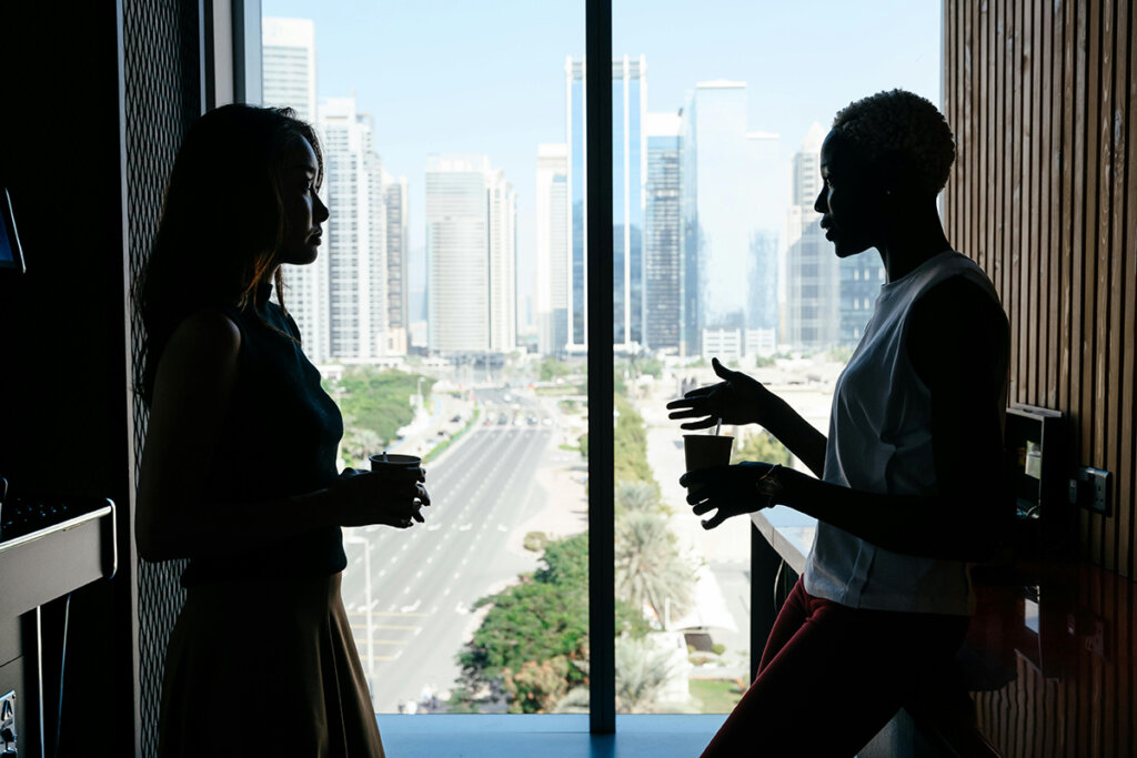 One woman employee meeting with another woman employee in an office kitchen to guide the mentoring relationship forward. 