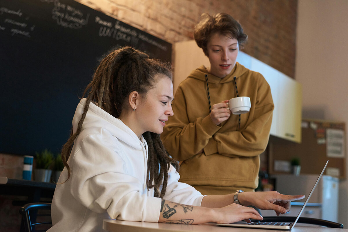 two female employees working on mentoring program design on laptop in office