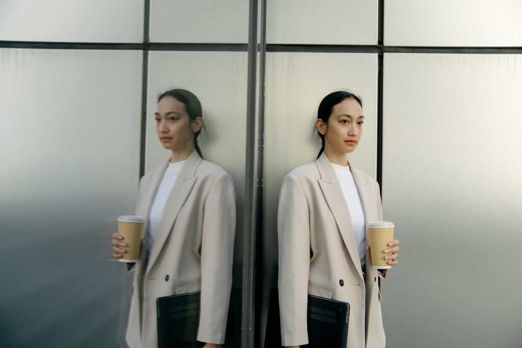 woman employee standing against building holding coffee contemplating belonging at her company