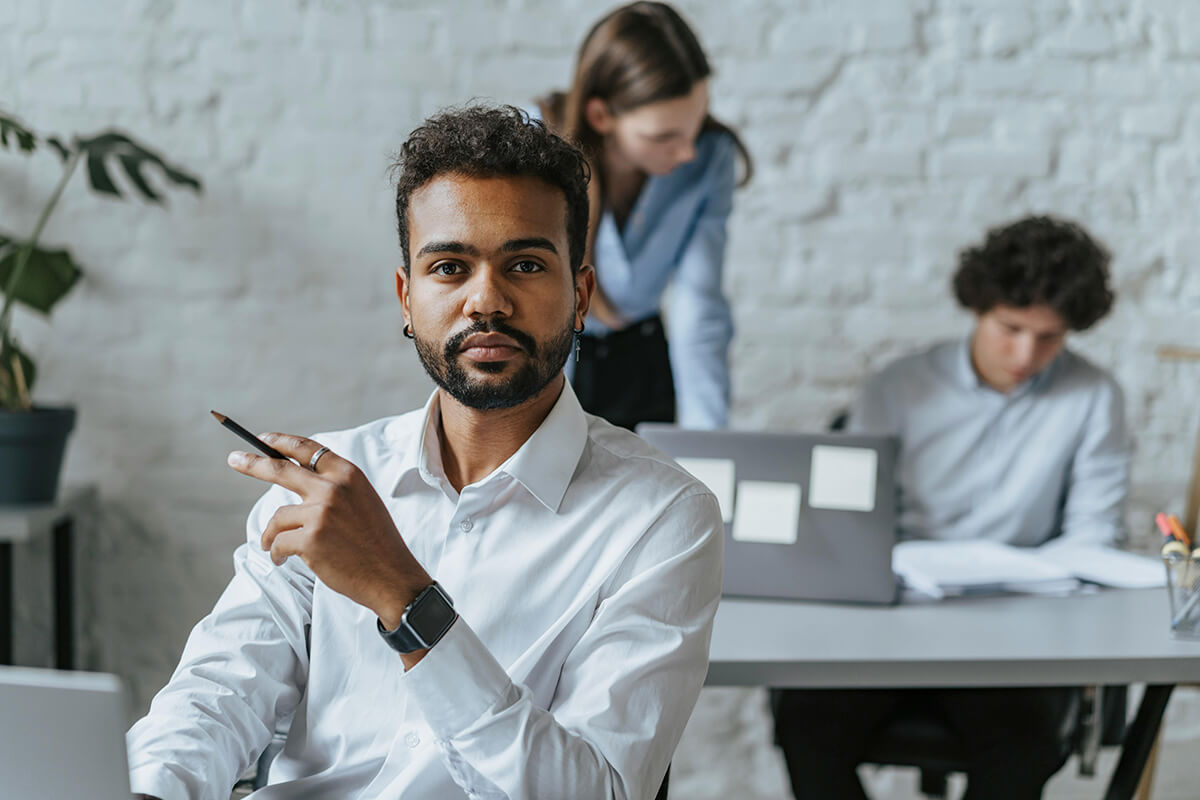 man holding a pen sitting at a desk in the office