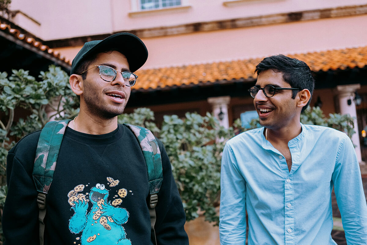 two male colleagues walk in the courtyard outside an office. They are discussing talent development and mentorship.