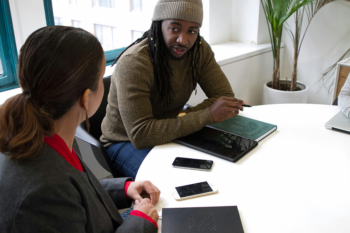 a male employee and a female employee sit at a table in a modern office discussing talent development strategies