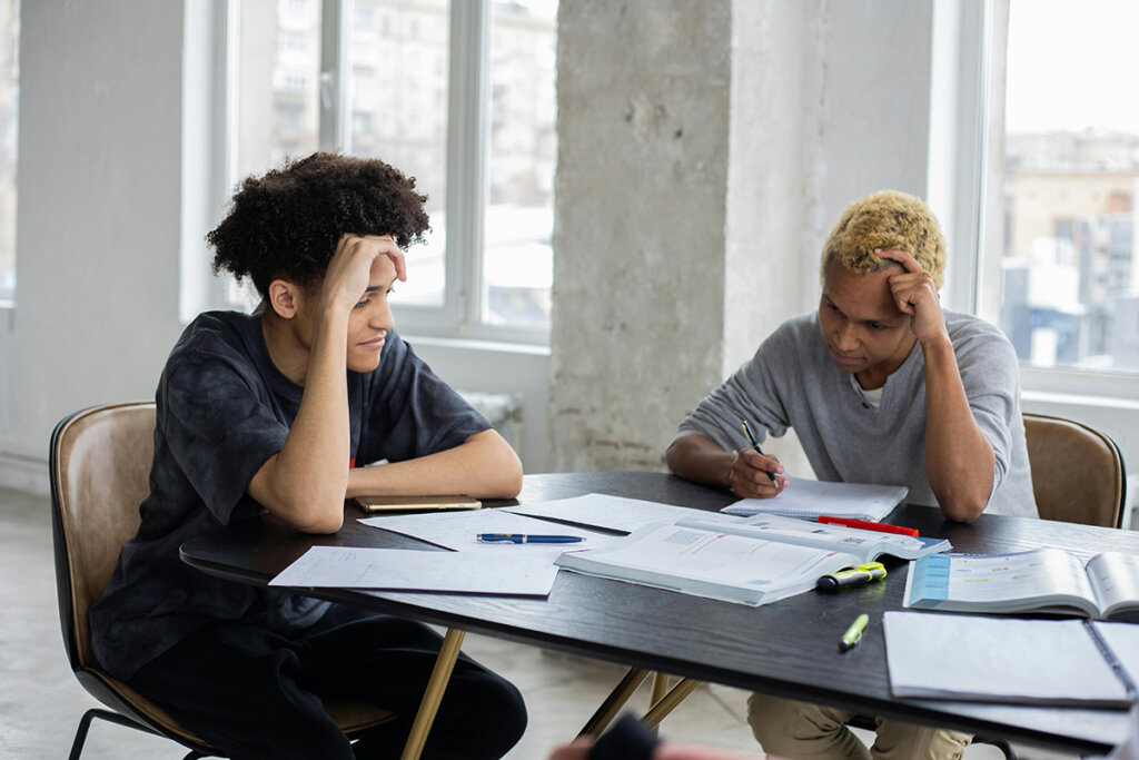 Two men sitting at a table in an office participating in peer-to-per learning group.