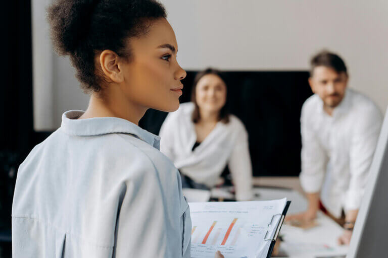 Woman employee leading a meeting with operational leadership, showcasing metrics and outcomes in a conference room