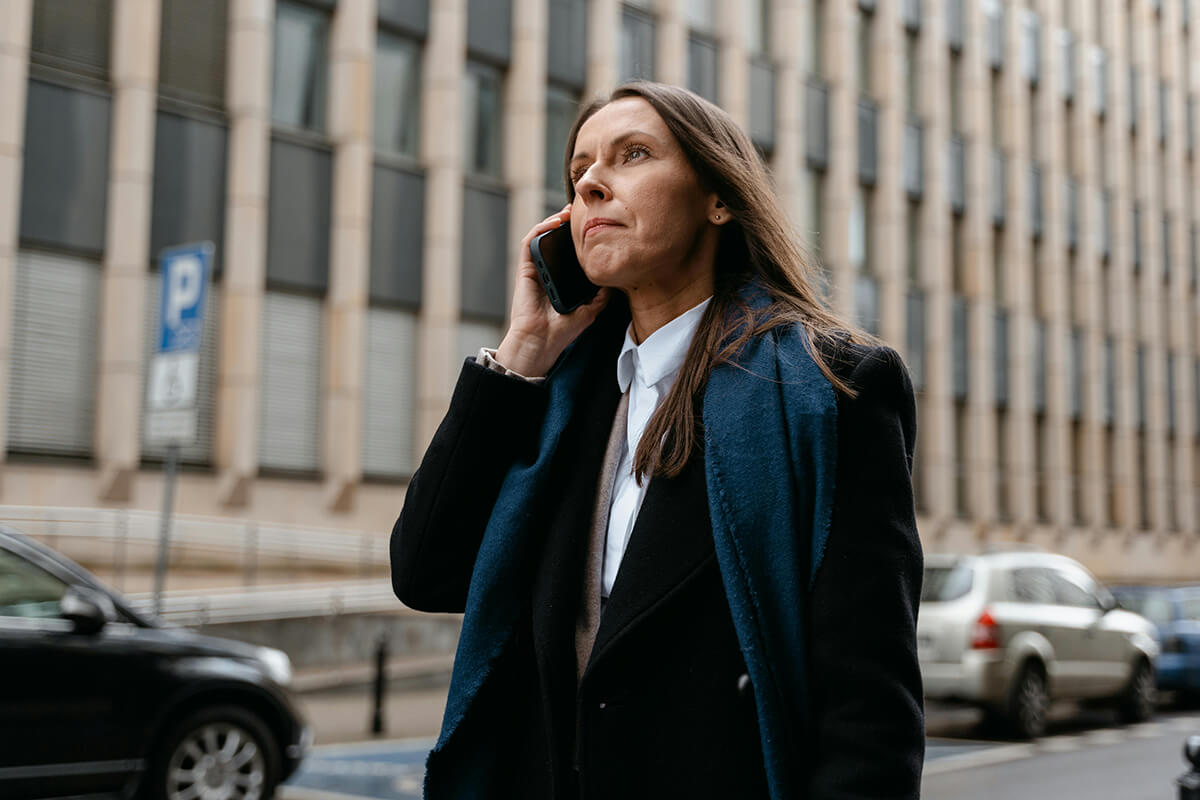 woman talking on a cellphone in a city street discussing leadership styles of the new executive hire