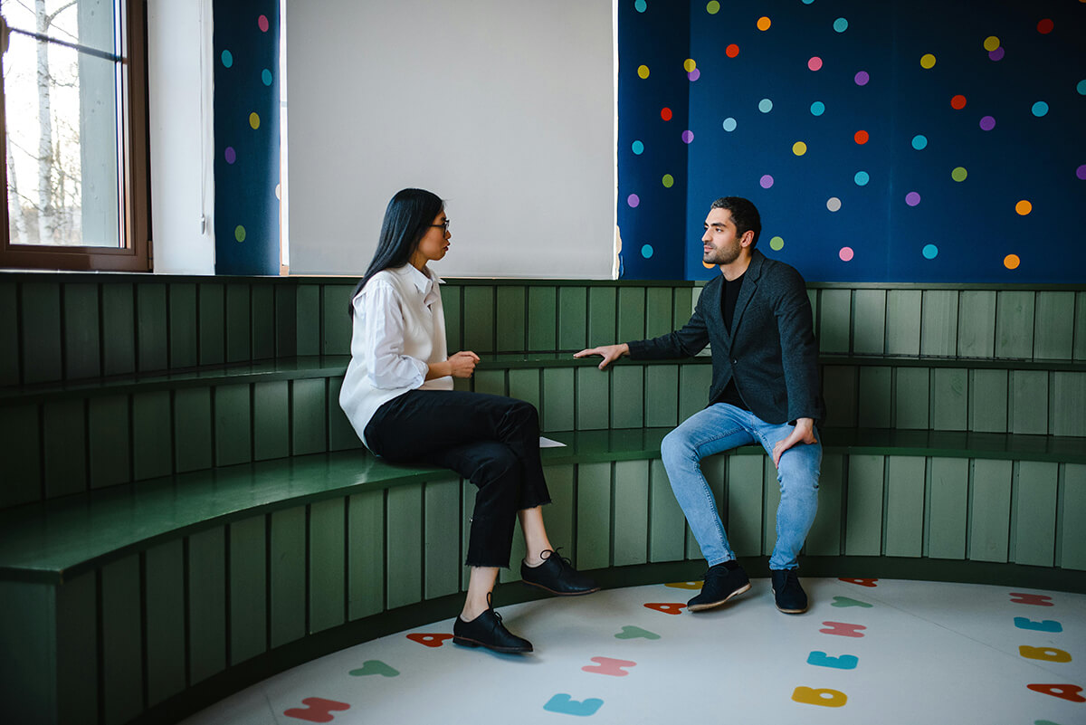 man and woman sitting in a rotunda in an office talking during a mentoring meeting