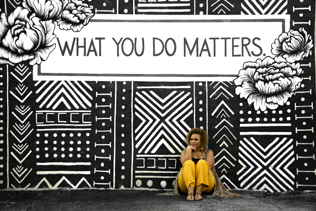 woman sitting in front of a mural that says What You Do Matters, thinking about how to motivate employees