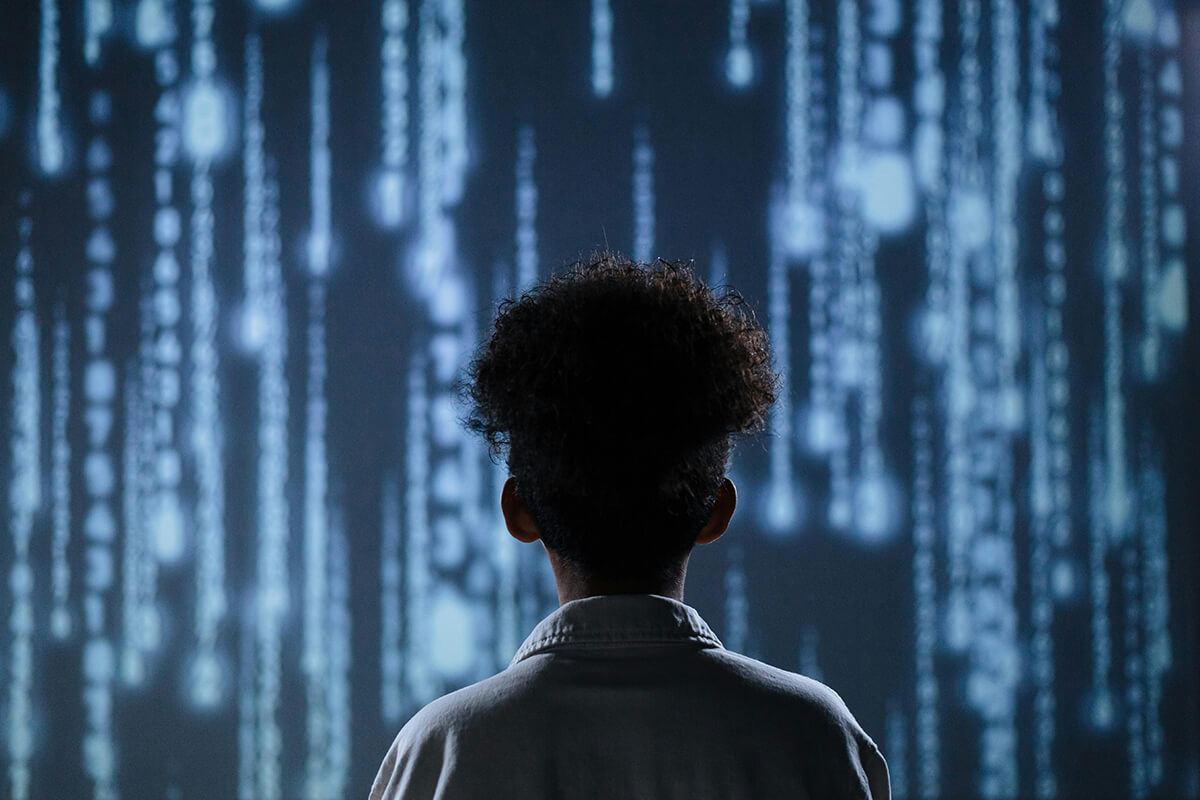 The back of a woman's head looking at a wall of code and images. She's learning about AI tools for HR use.