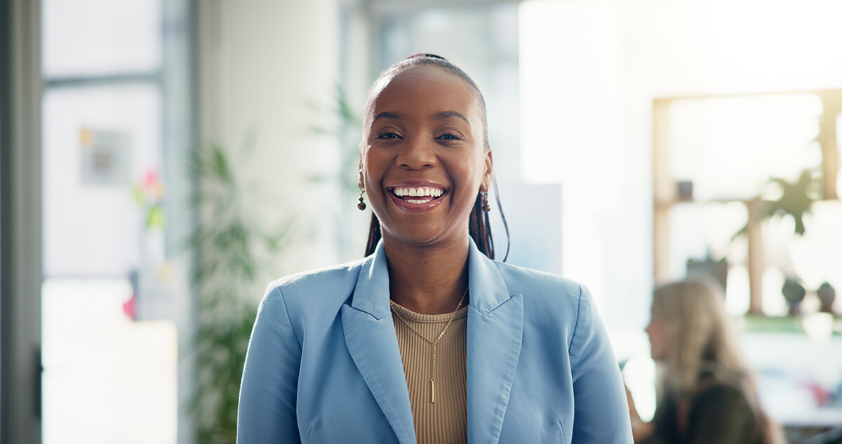 black woman standing in a modern office smiling with a growth mindset