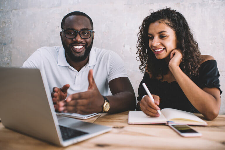 two colleagues sitting at a desk looking at a laptop, discussing AI in mentoring relationships