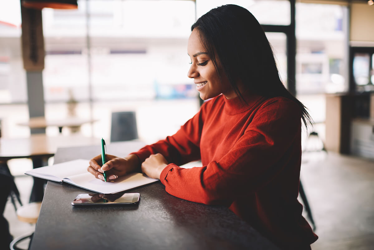 Woman sitting in a cafe working on her professional goals' list