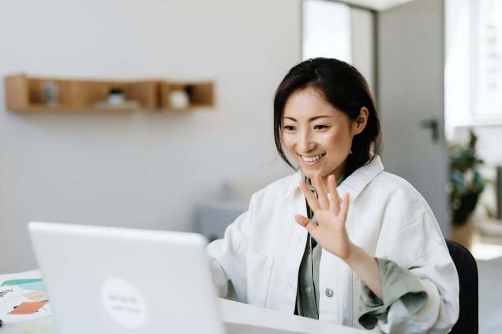 A person waving at a laptop. Video conference concept.