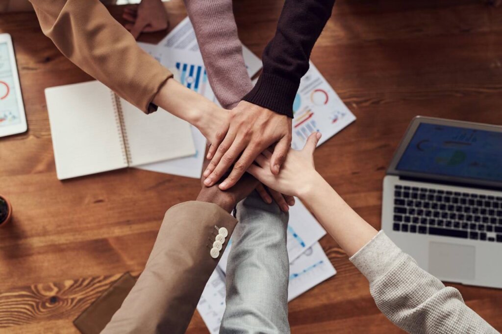 Close-up on colleagues joining hands in the center of a conference table
