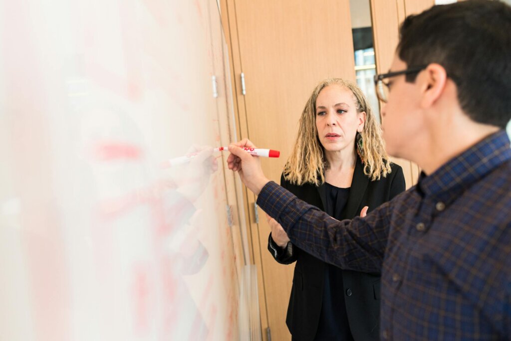 Two colleagues use a whiteboard