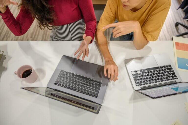 A pair of professionals discuss what they're seeing on a laptop screen.