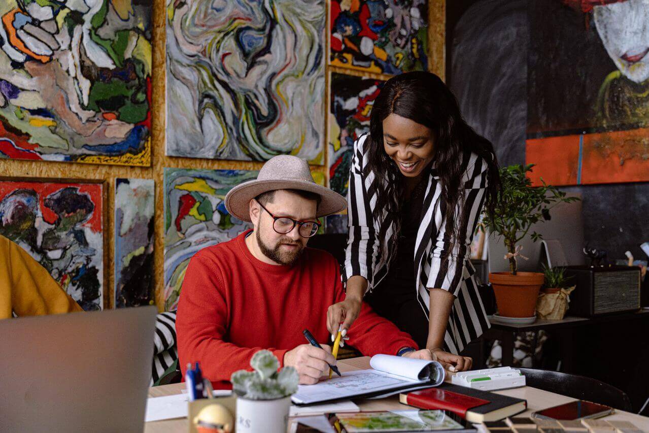 AI mentoring tools concept - A mentor works with a mentee in a bright, art-filled creative office