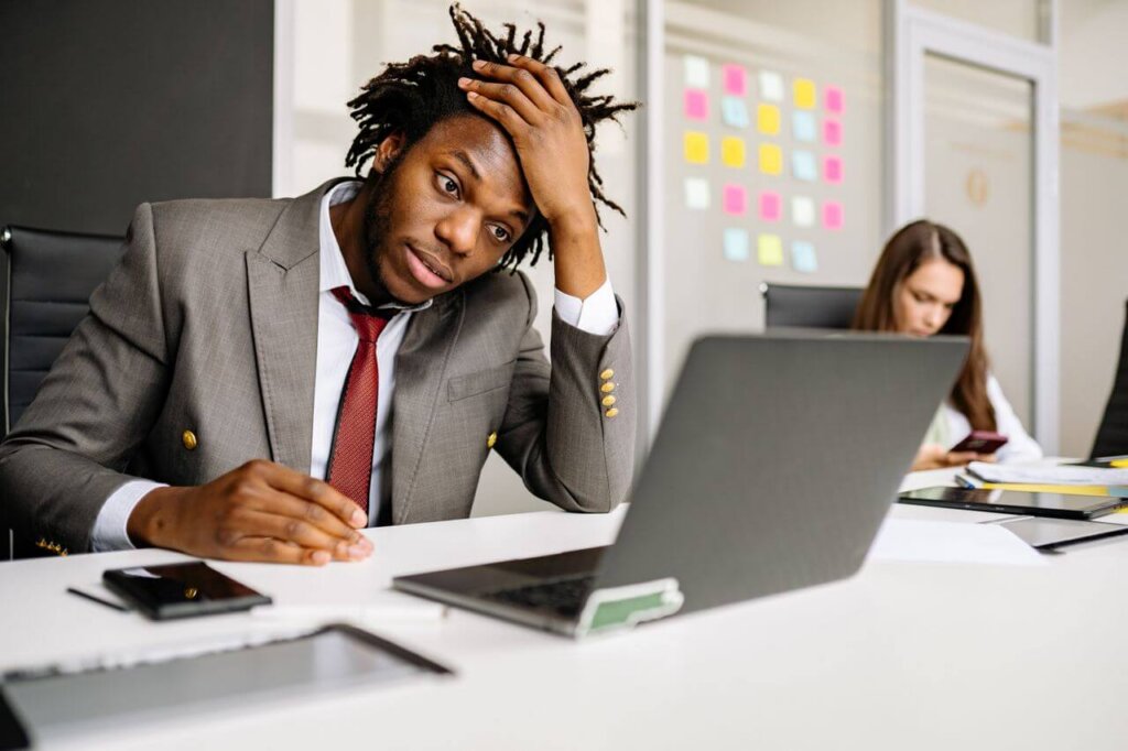 A stressed-looking professional looks at his laptop