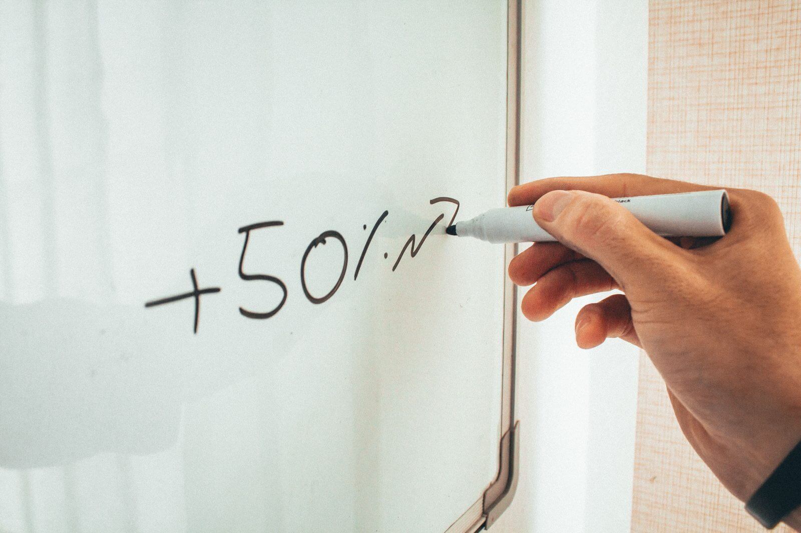 Hand writing a 50 percent improvement figure on a whiteboard, representing mentoring program ROI